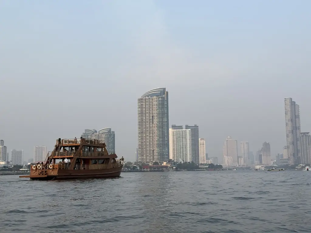 Elvebåt og Bangkoks skyline langs Chao Phraya